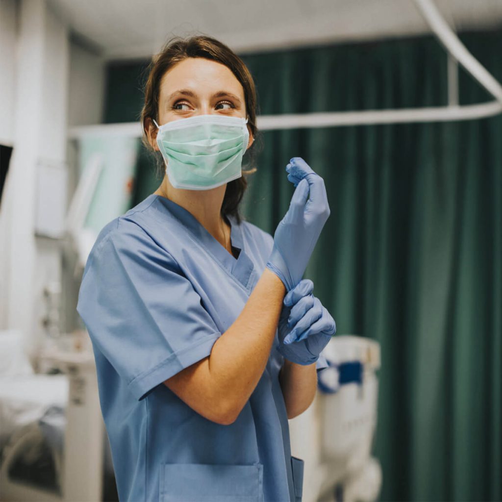 Médecin femme avec un masque enfilant des gants